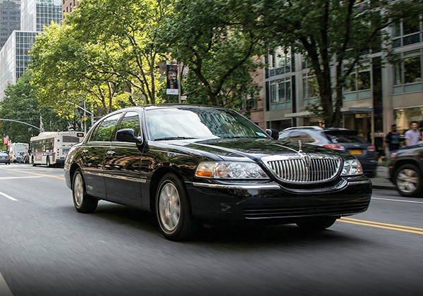 Black sedan driving city street