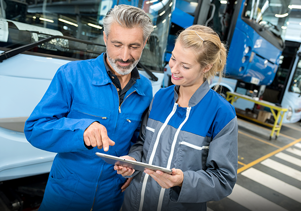 People discussing tablet near bus